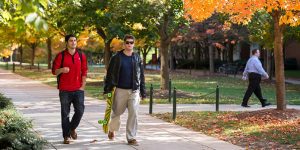 Two students walk on campus in the fall colors