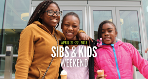 black woman in a yellow hoodie with two younger siblings wearing pink
