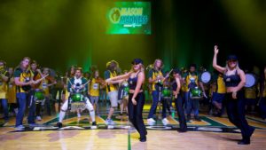 Mason Madness: people dancing and drumming in green and gold