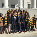 Students in Mason scarves standing with Dr. Cabrera on government building steps outside