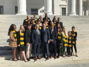 Students in Mason scarves standing with Dr. Cabrera on government building steps outside