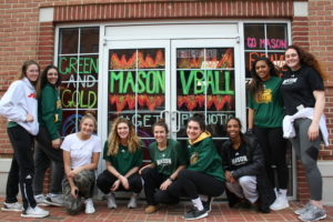 Team of students in front of a retail space with windows painted for Homecoming