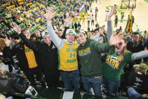 students in green and gold at a basketball game