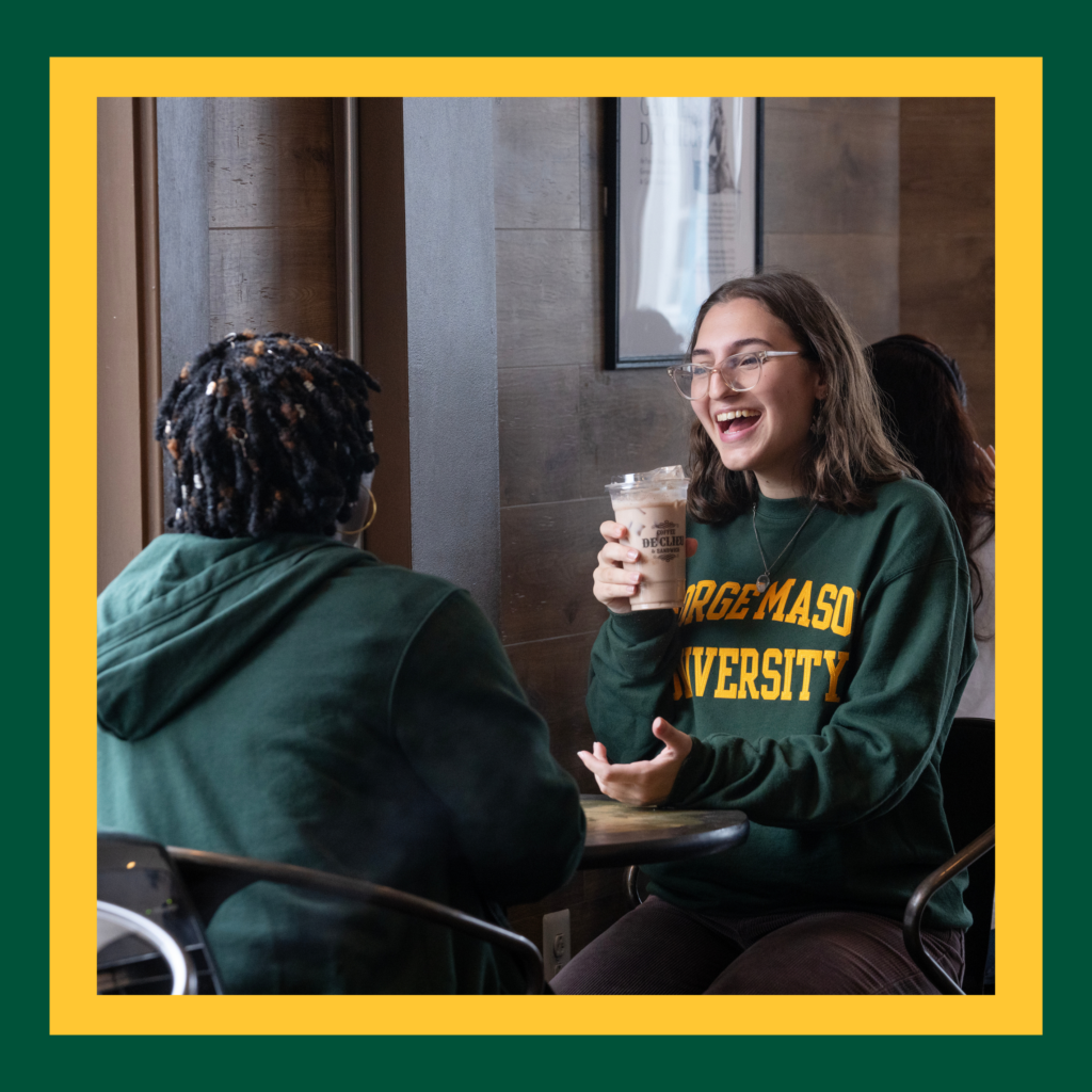 Mason Faculty and Student chatting in a coffee shop.