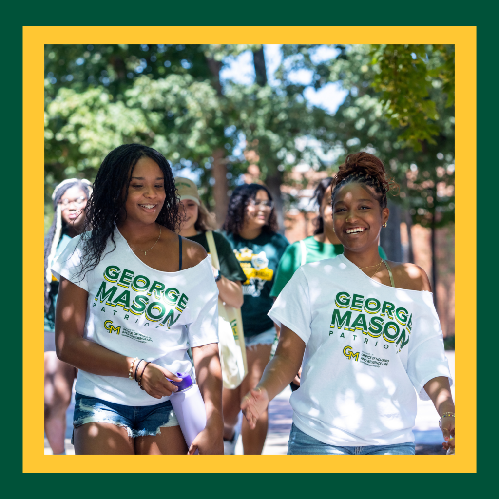 Two George Mason students walking on campus in branded t-shirts.