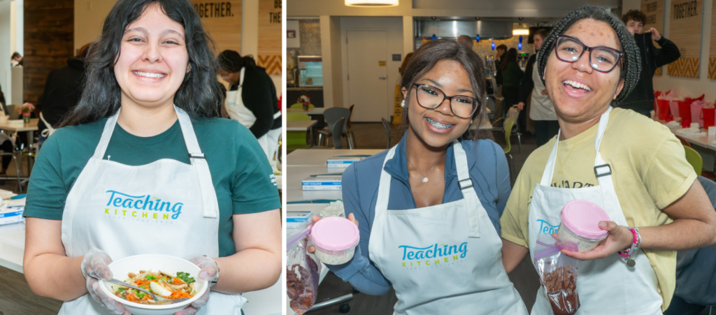 Three students wearing Teaching Kitchen aprons smiles while holding the food they prepared during a Mason Dining Teaching Kitchen session.